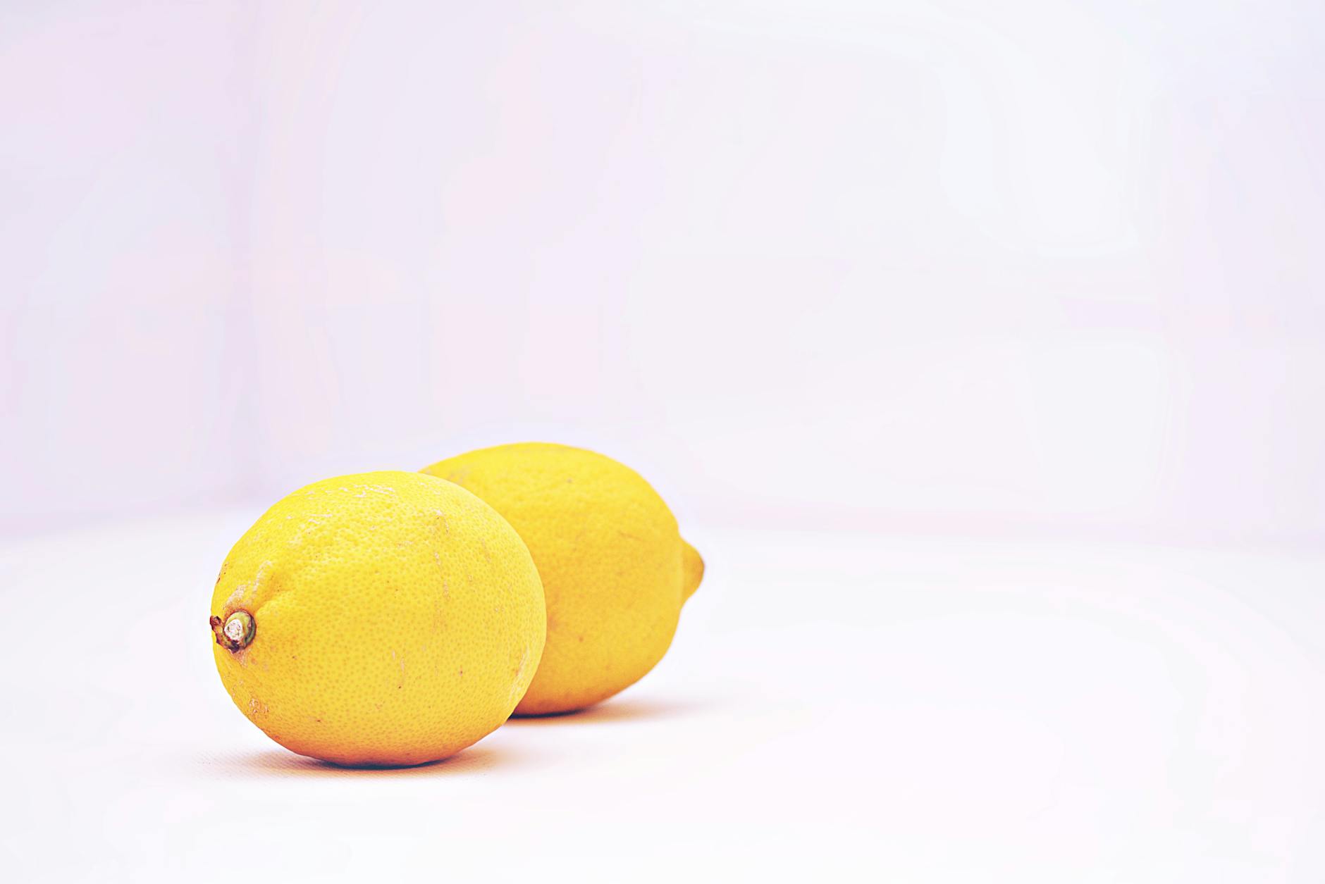 Hand holding a fresh lemon on a soft pink background, representing fresh perspectives on solo pleasure