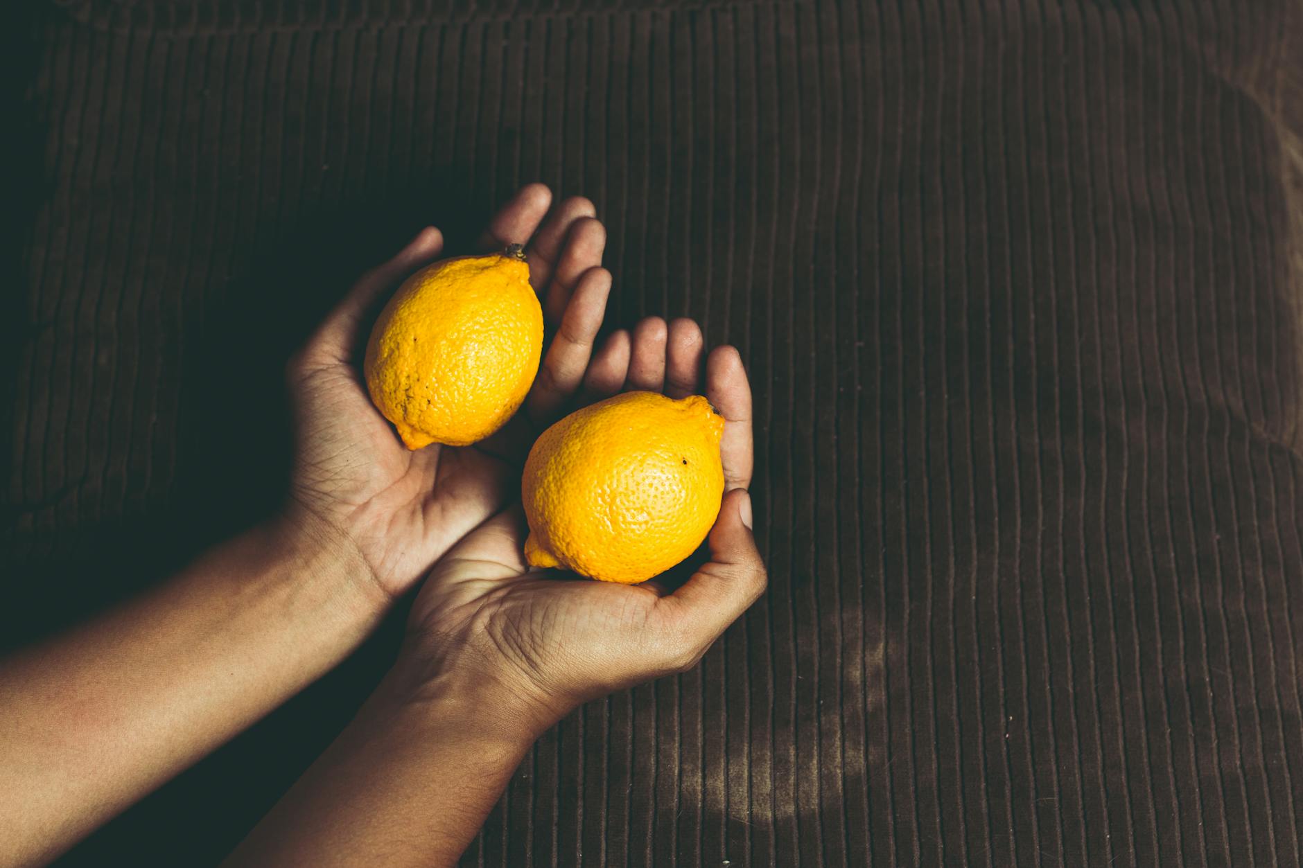 Two fresh lemons held in cupped hands, symbolizing natural pleasure and wellness