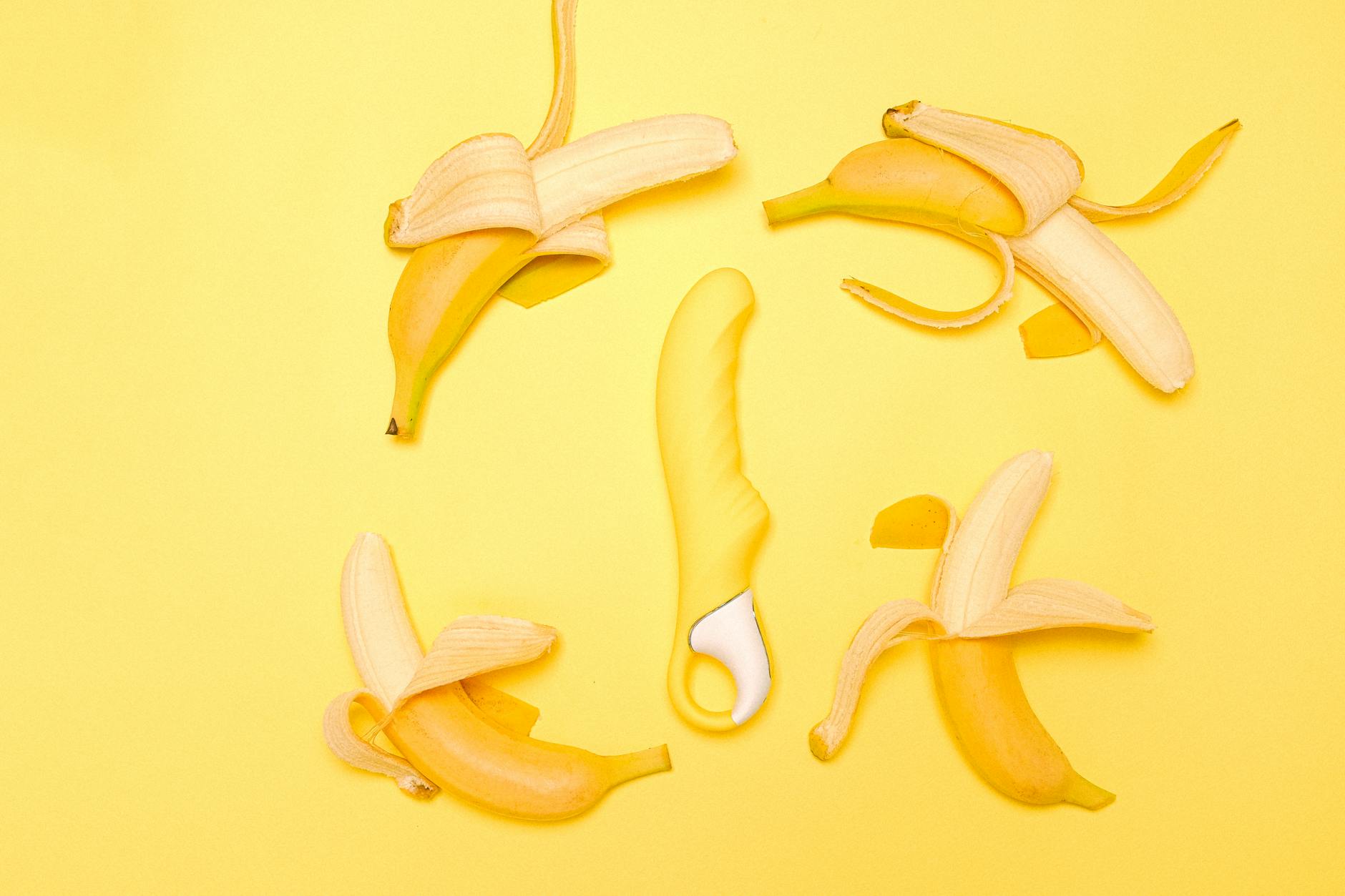 Yellow silicone vibrator surrounded by peeled lemons on pastel background, symbolizing pleasure and reconnection.