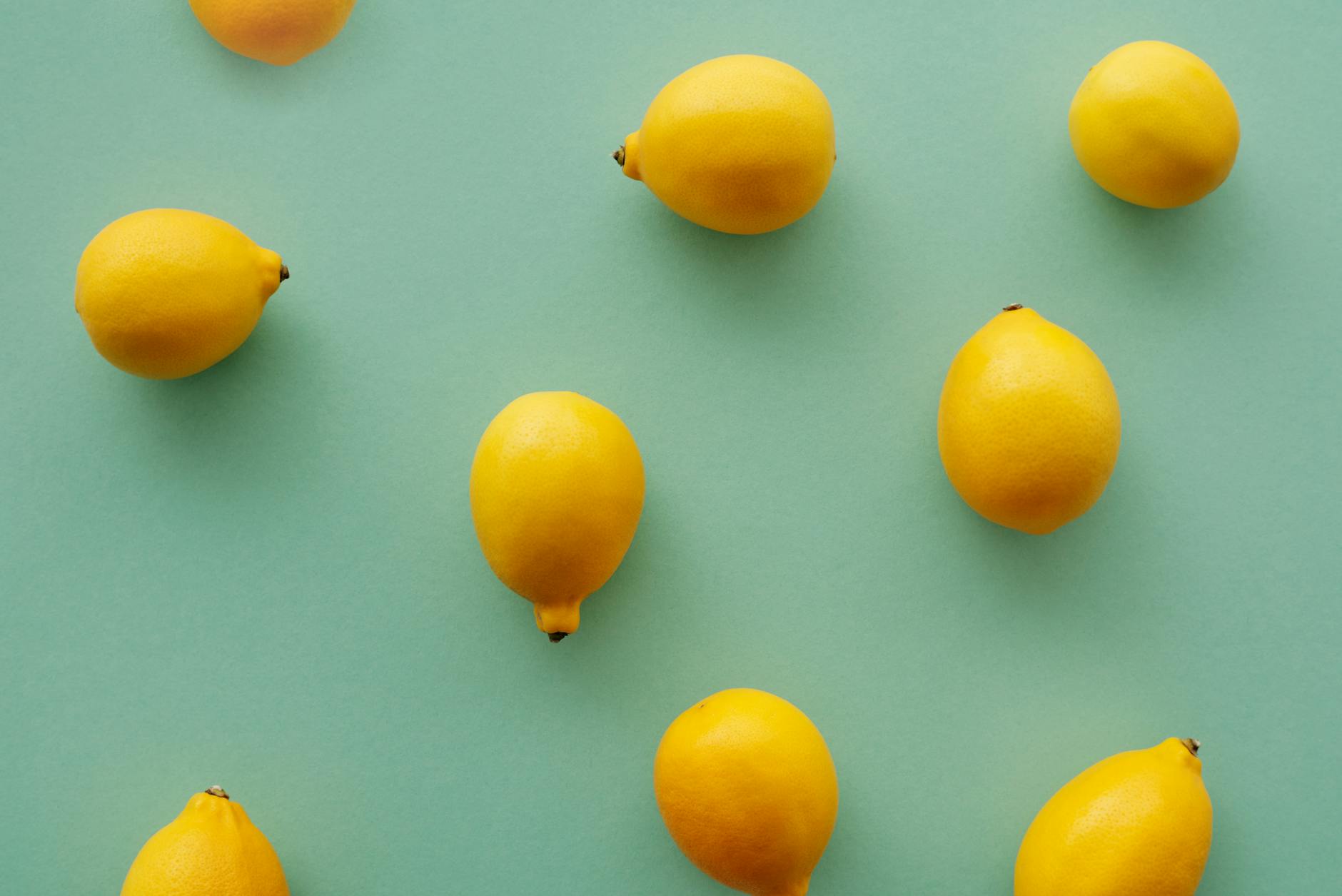 Bright yellow lemons arranged on a pastel green background, symbolizing the Lemon Vibrator by Hello Nancy