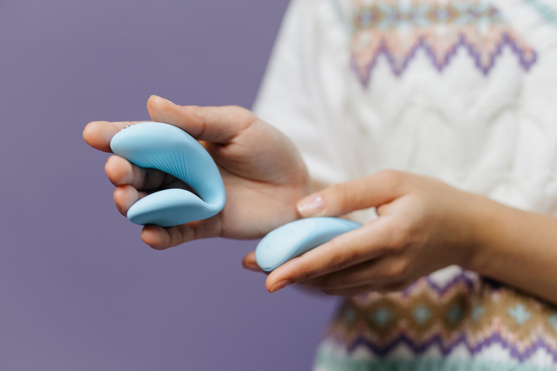 A young couple standing together indoors, holding a blue vibrator, symbolizing modern intimacy and openness.