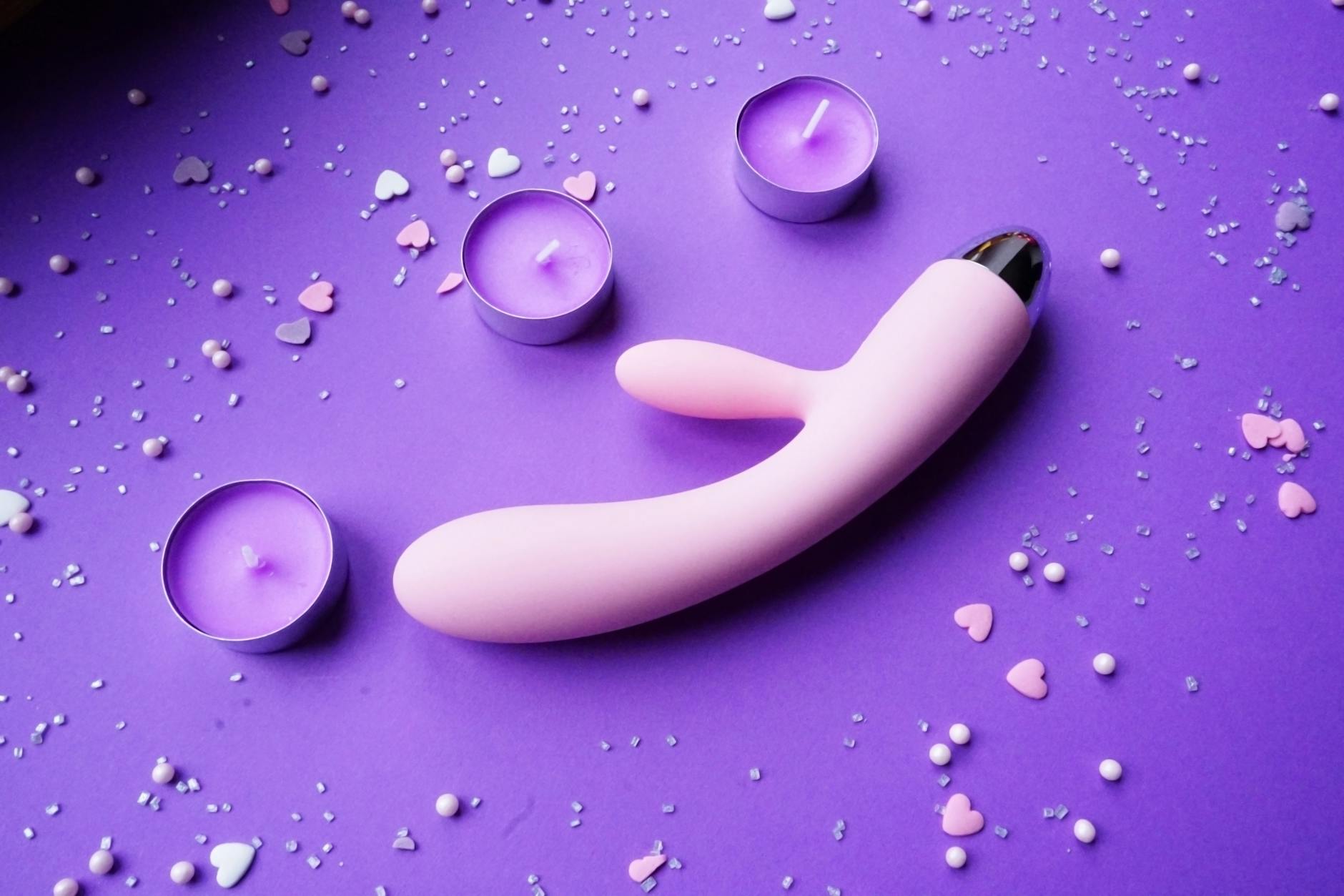 Intimate moment with a pink vibrator surrounded by romantic elements and candles